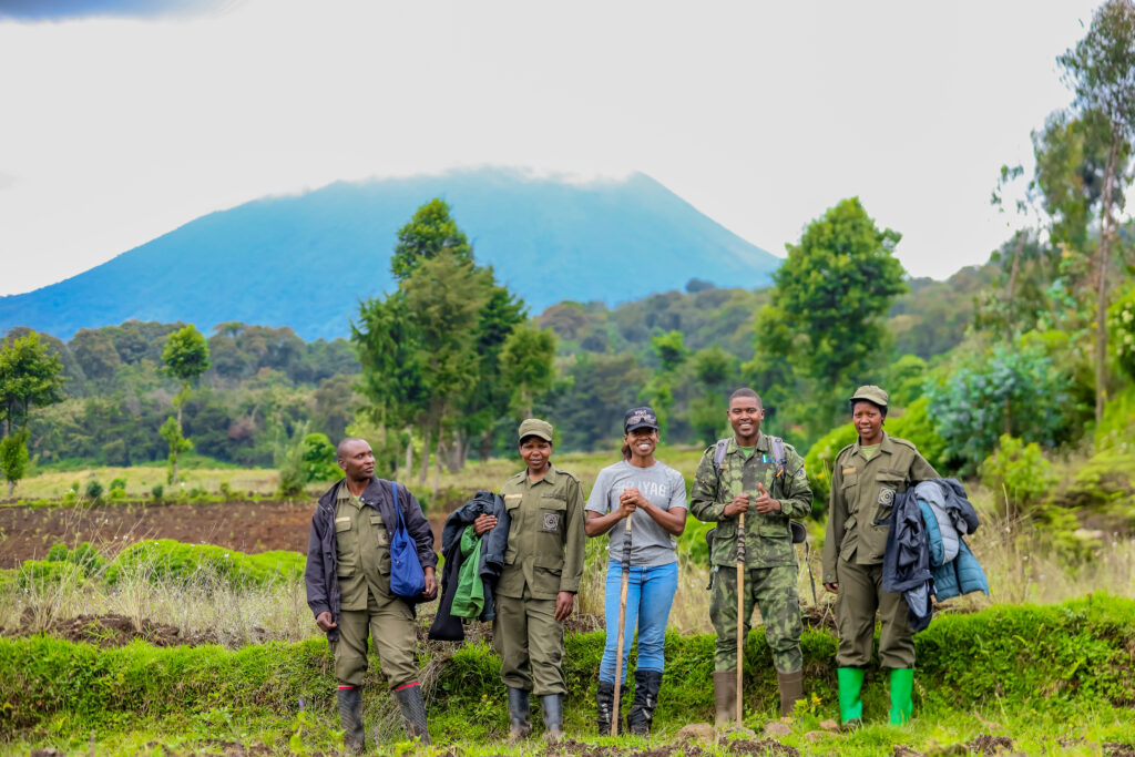 Rwandan park rangers and a tourist posing against the backdrop of Volcanoes National Park. Rwanda’s strong conservation efforts and security measures make it the safest travel destination for eco-tourism and wildlife experiences.