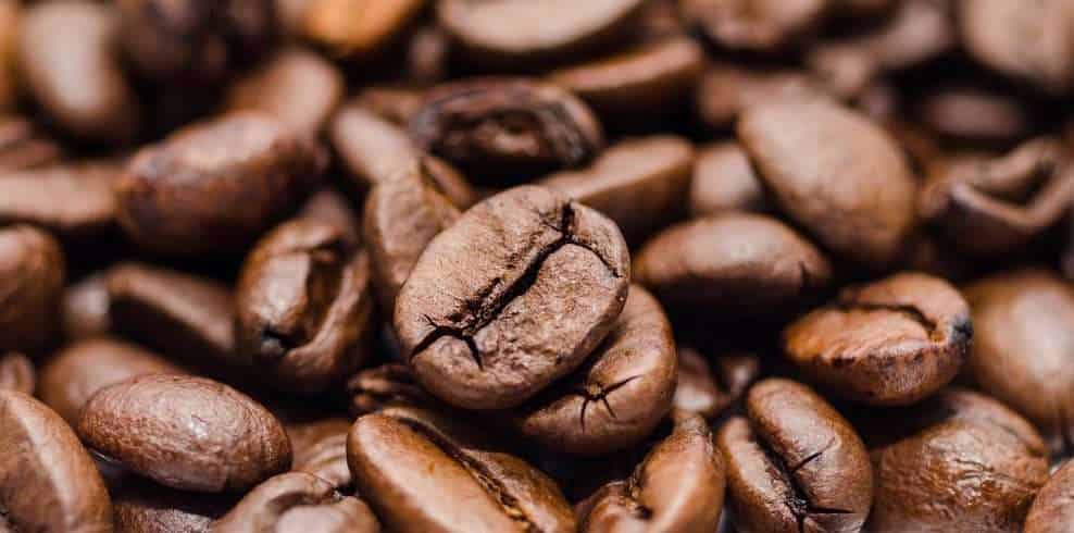 Close-up of roasted coffee beans with rich, dark brown tones, showcasing their texture and natural oils. Perfect for illustrating high-quality Arabica coffee from Rwanda.