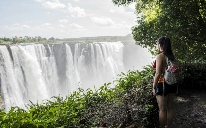 Young female tourist looking out at Victoria Falls, Zimbabwe, Africa